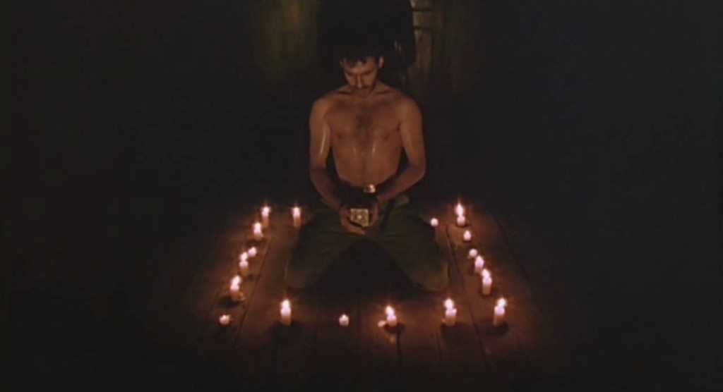 Frank kneels in a candle-lit circle, preparing to open the box