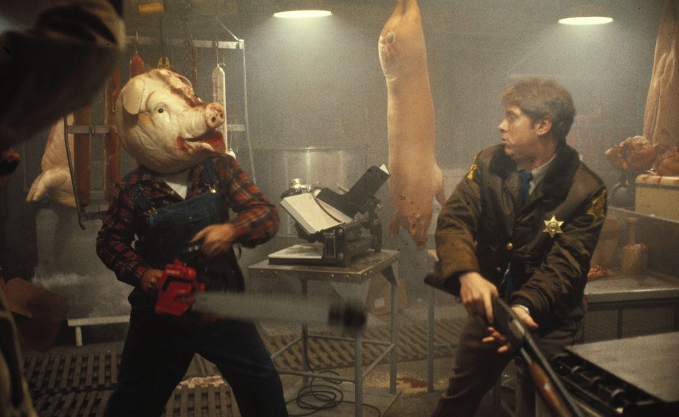 Yep. That's Farmer Vincent. Wearing a pig head over top of his own, brandishing a chainsaw against the local sheriff. Just another day here at Motel Hell.
