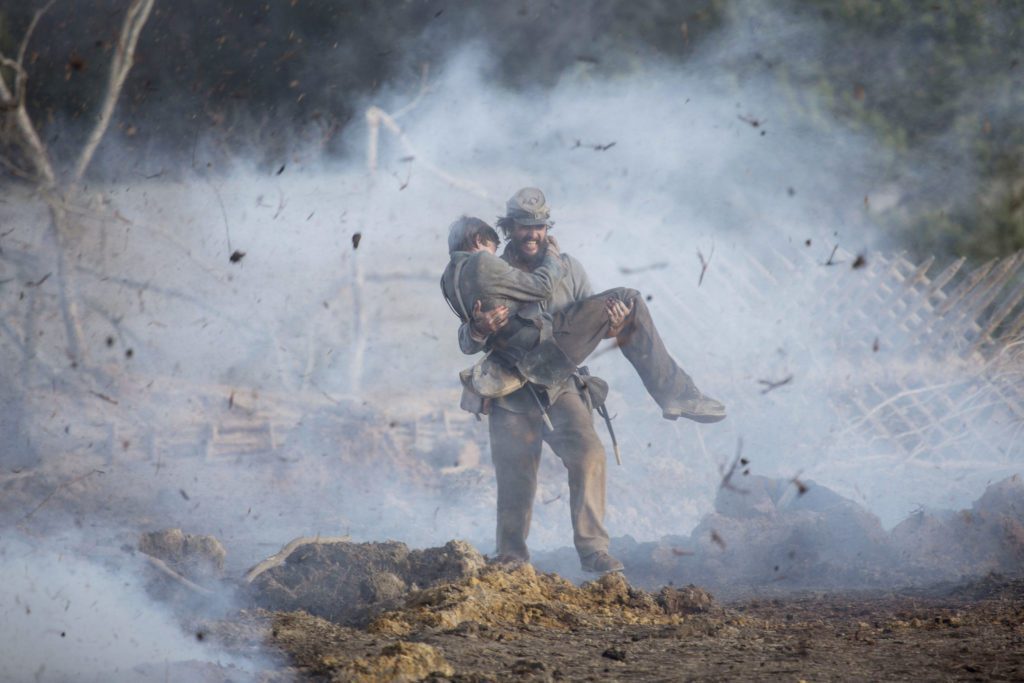 Newton (Matthew McConaughey) carries Daniel (Jacob Lofland) across an active battlefield