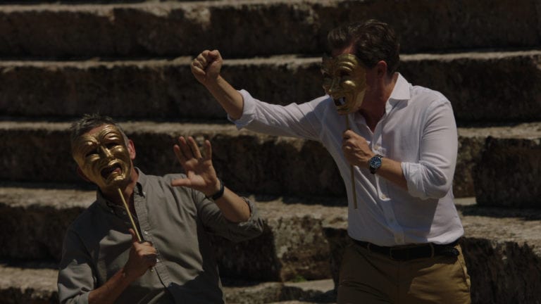 Still - credit The Trip to Greece - Rob, wearing a comedy mask, threatens Steve, wearing a tragedy mask